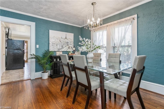 dining space with hardwood / wood-style flooring, ornamental molding, and an inviting chandelier