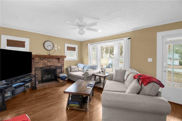 living room with dark hardwood / wood-style flooring, a brick fireplace, and ceiling fan