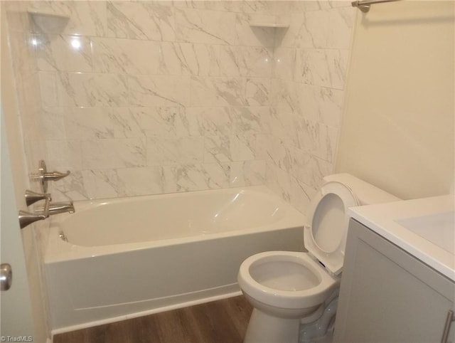 full bathroom with toilet, vanity, tiled shower / bath, and hardwood / wood-style floors