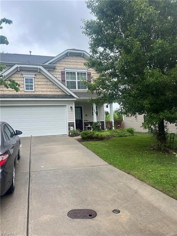 view of front of home with driveway, a front lawn, an attached garage, and a porch