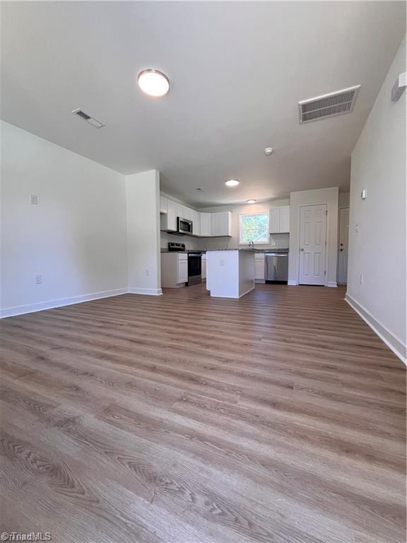 1609 Hardie St, Greensboro, NC 27403 - unfurnished living room featuring baseboards and wood finished floors
