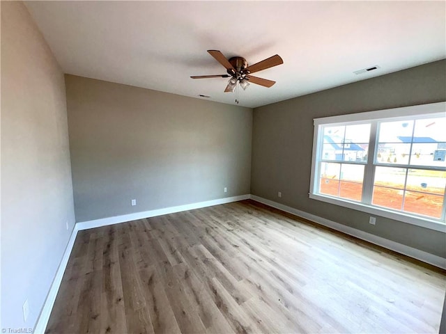 empty room with light wood-style floors, visible vents, and baseboards