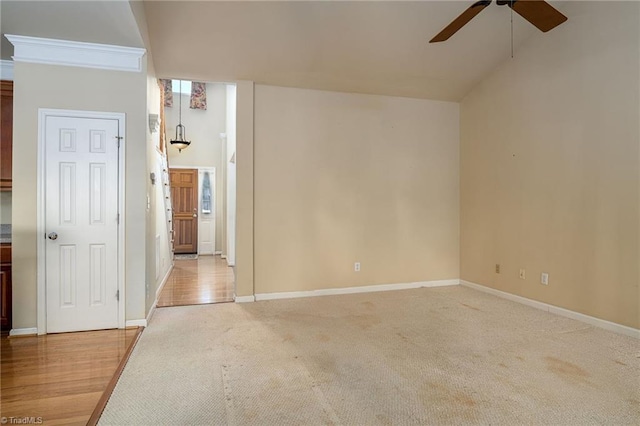 spare room with baseboards, light carpet, and a ceiling fan