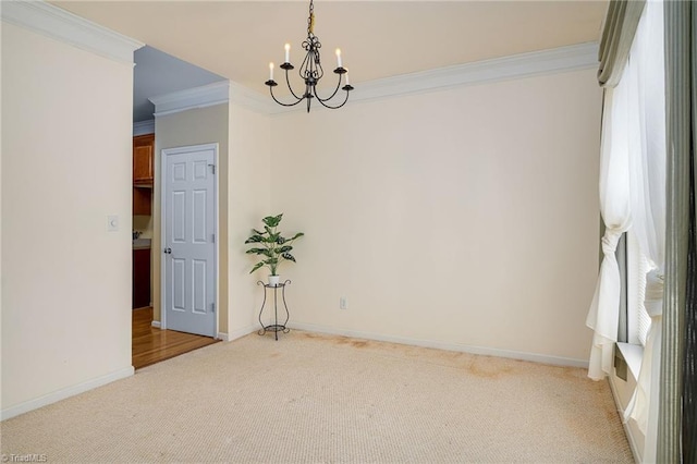 carpeted spare room featuring an inviting chandelier, crown molding, and baseboards