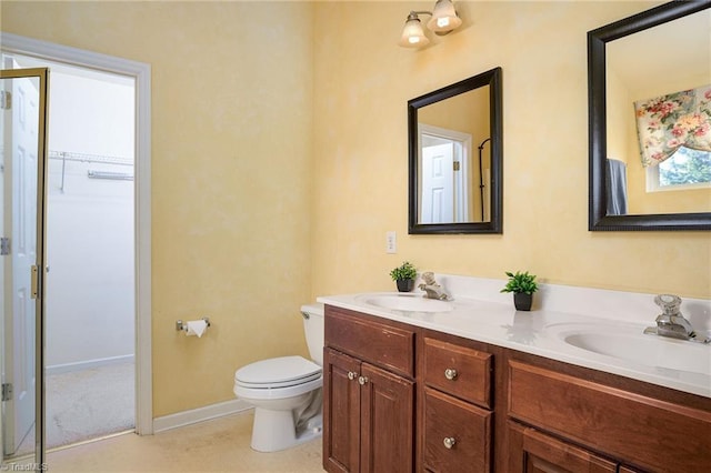 full bath featuring double vanity, toilet, baseboards, and a sink