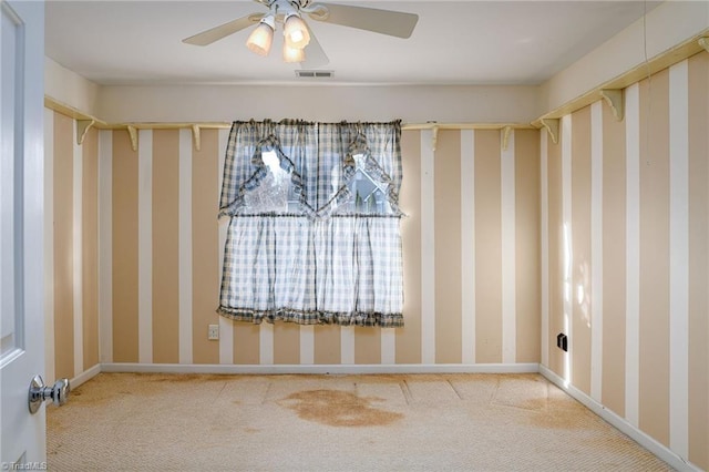 carpeted empty room with visible vents, baseboards, and a ceiling fan