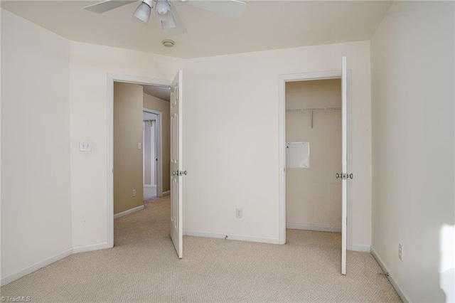 unfurnished bedroom with a closet, a spacious closet, baseboards, and carpet floors