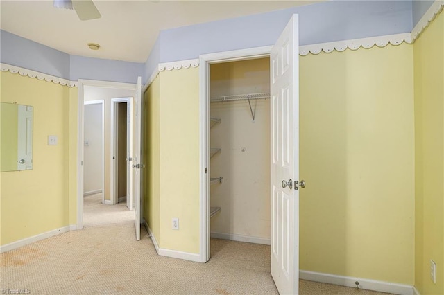 unfurnished bedroom with a walk in closet, carpet, baseboards, and a closet