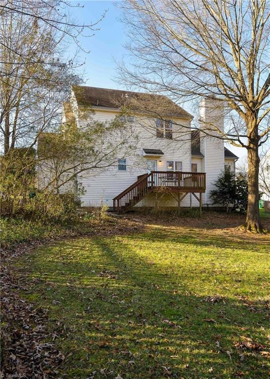 exterior space featuring a wooden deck, a lawn, and a chimney