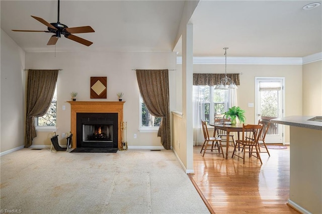 living area with baseboards, visible vents, a fireplace with flush hearth, ornamental molding, and light wood-type flooring