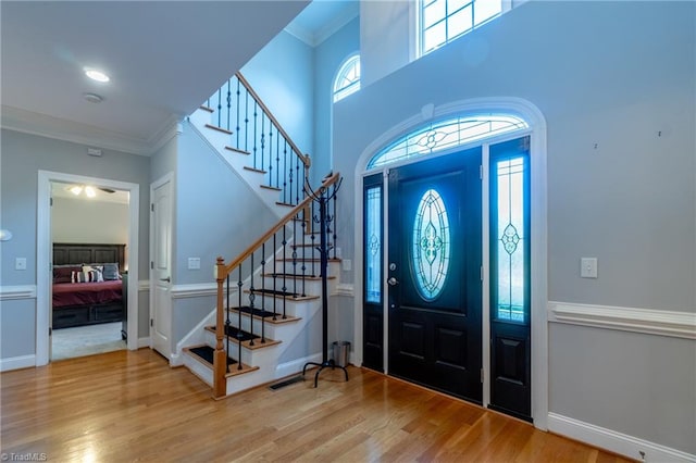 foyer featuring hardwood / wood-style flooring, ornamental molding, a high ceiling, and plenty of natural light