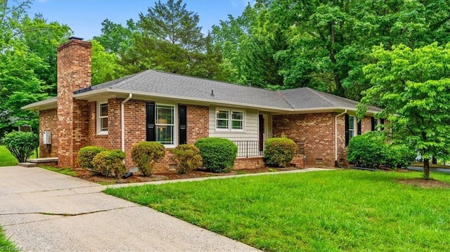 ranch-style home with a chimney, a front lawn, crawl space, brick siding, and a shingled roof