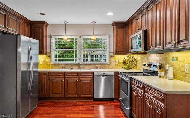 kitchen featuring stainless steel appliances, a sink, dark wood finished floors, light countertops, and recessed lighting