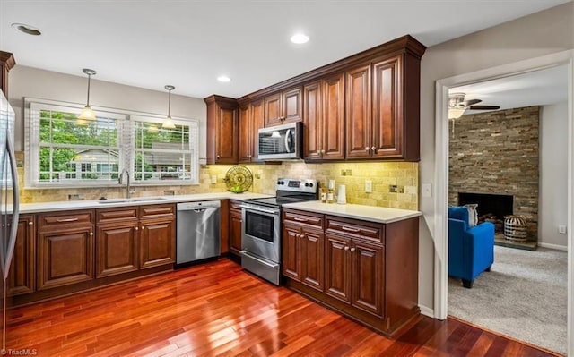 kitchen with stainless steel appliances, a sink, light countertops, dark wood-type flooring, and recessed lighting