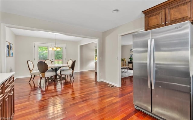 dining space featuring wood finished floors, a chandelier, and baseboards