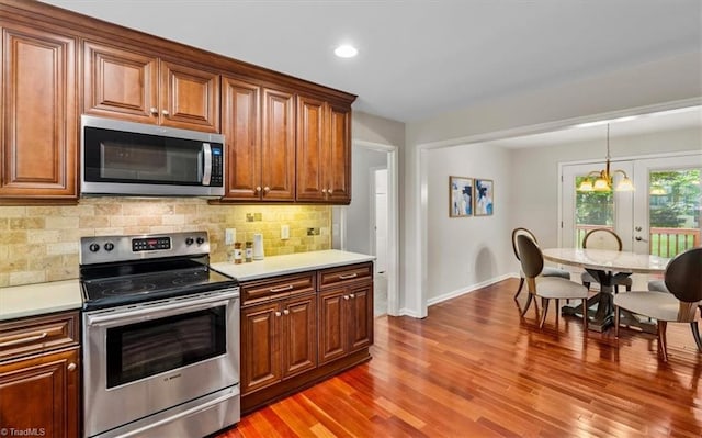 kitchen featuring stainless steel appliances, baseboards, tasteful backsplash, light countertops, and wood finished floors