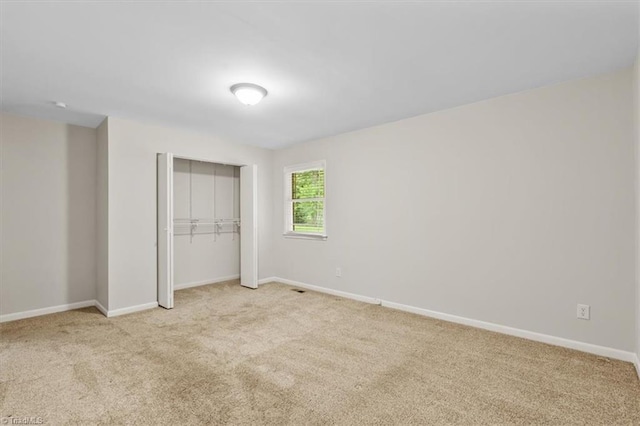 unfurnished bedroom with light colored carpet, baseboards, and a closet