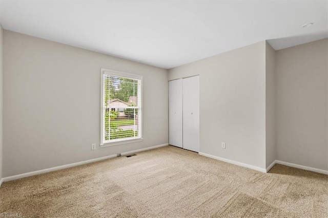 unfurnished bedroom with carpet, baseboards, and a closet