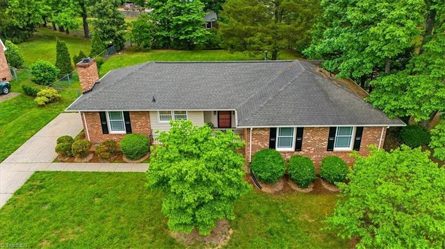 view of front of house featuring brick siding, a front lawn, a chimney, and a shingled roof