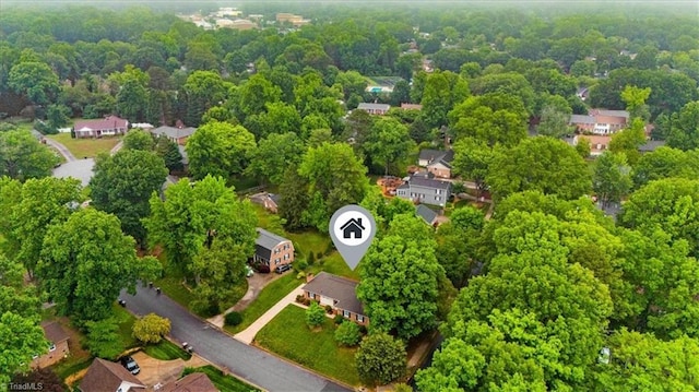 aerial view of property's location featuring a forest and nearby suburban area