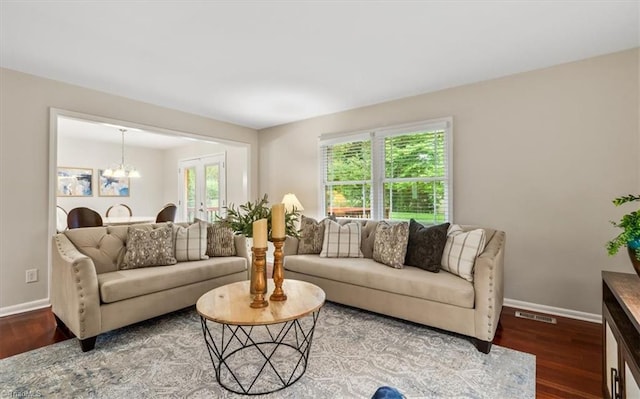 living area with baseboards, wood finished floors, and a chandelier