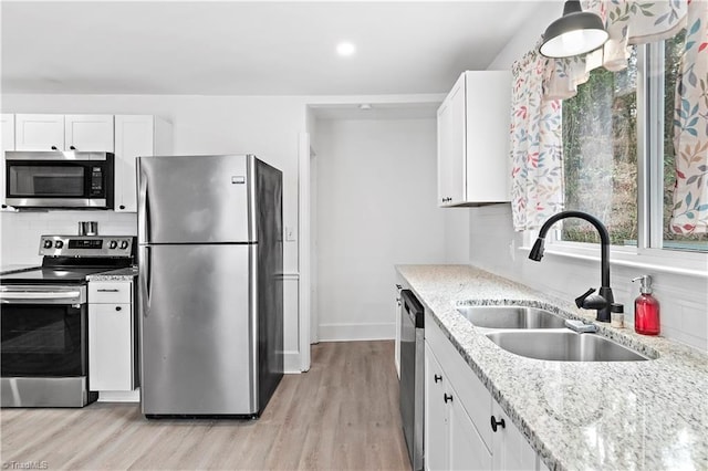 kitchen with stainless steel appliances, sink, white cabinets, and light stone counters