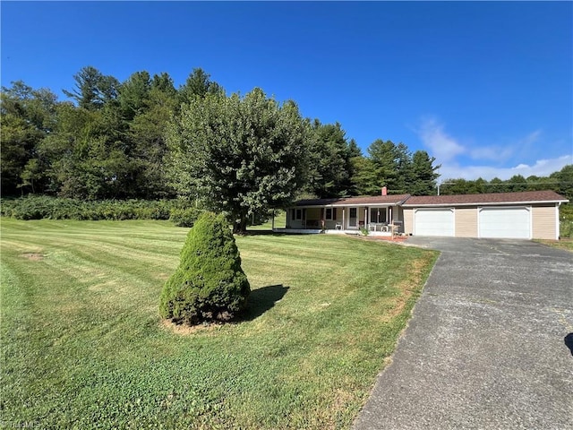 view of front of house with aphalt driveway, a garage, a porch, and a front lawn