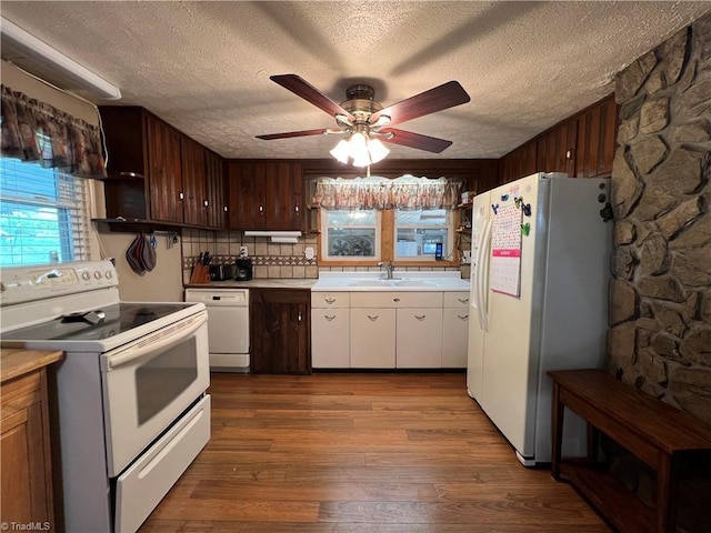 kitchen featuring white appliances, wood finished floors, a sink, light countertops, and decorative backsplash