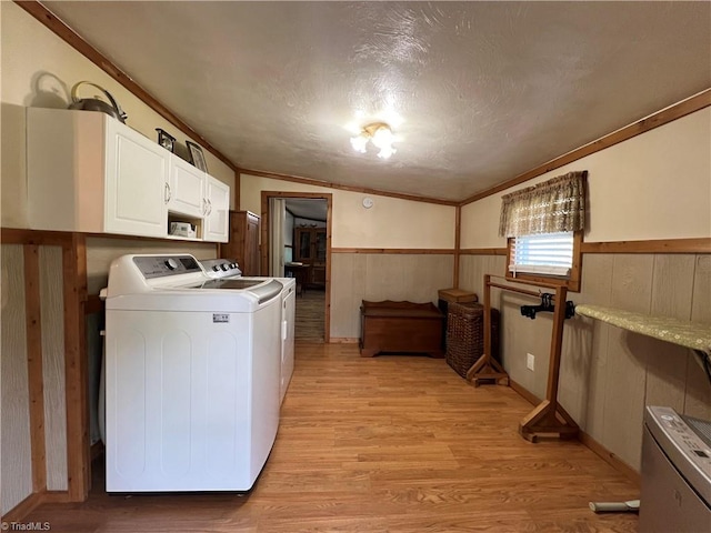 laundry room featuring cabinet space, a wainscoted wall, light wood-style flooring, ornamental molding, and washer and dryer