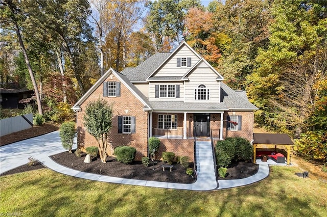 traditional-style home with a shingled roof, covered porch, brick siding, and a front lawn