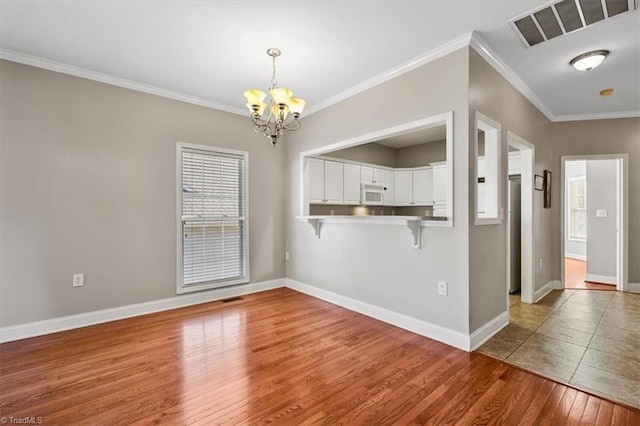 unfurnished dining area with a chandelier, ornamental molding, and wood-type flooring