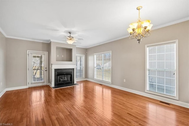 unfurnished living room featuring ceiling fan with notable chandelier, wood-type flooring, and crown molding