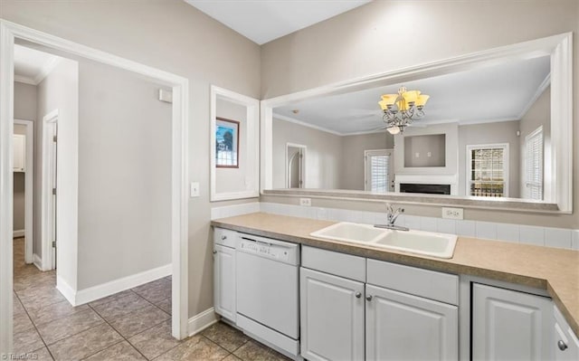 kitchen with sink, ornamental molding, white cabinets, and white dishwasher