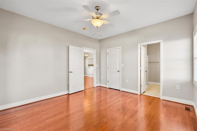 unfurnished bedroom with ceiling fan, ensuite bathroom, and light hardwood / wood-style floors