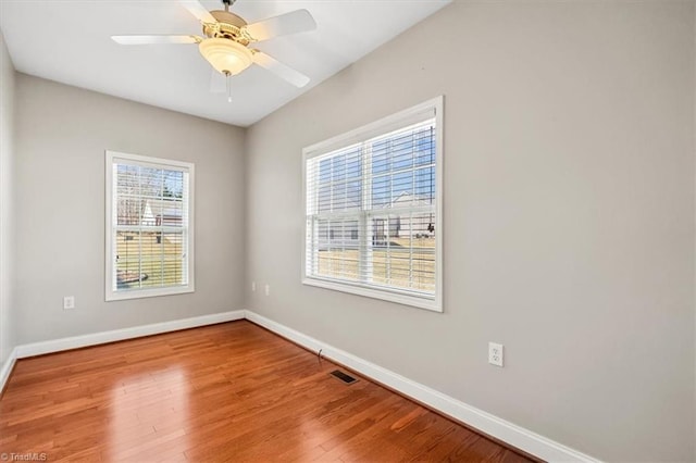 spare room with a healthy amount of sunlight, hardwood / wood-style flooring, and ceiling fan