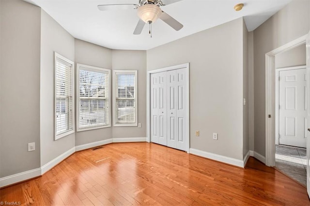 unfurnished bedroom with ceiling fan, wood-type flooring, and a closet