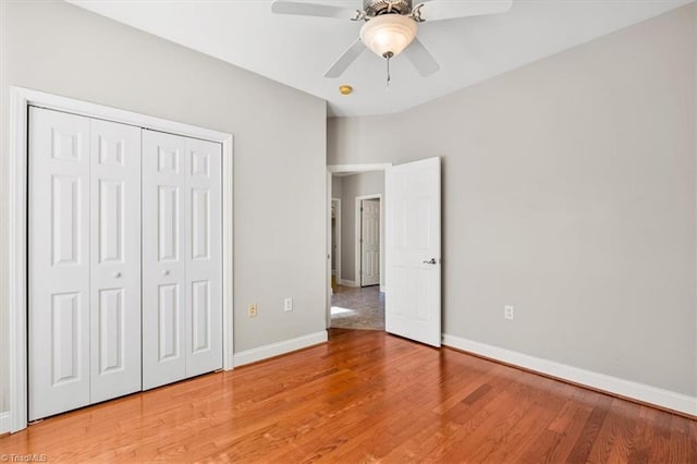 unfurnished bedroom featuring hardwood / wood-style floors, a closet, and ceiling fan