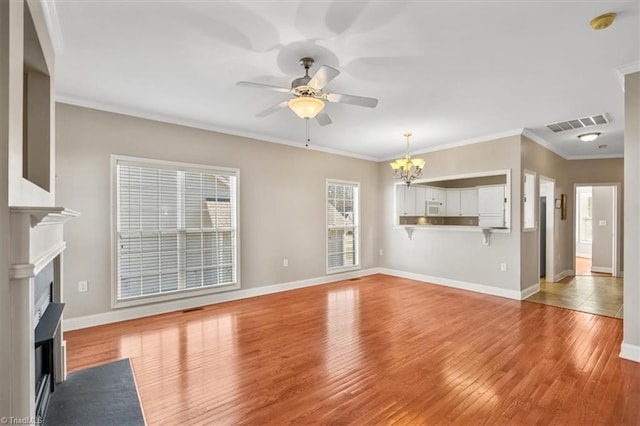 unfurnished living room with ceiling fan with notable chandelier, light hardwood / wood-style flooring, and ornamental molding