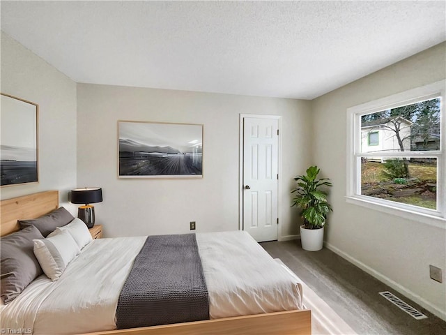 bedroom featuring visible vents, a textured ceiling, and baseboards