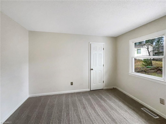 carpeted empty room with visible vents, a textured ceiling, and baseboards