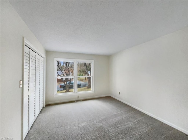 unfurnished bedroom featuring visible vents, baseboards, carpet flooring, a closet, and a textured ceiling