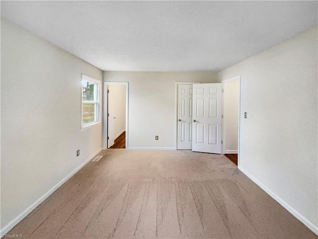 unfurnished bedroom featuring visible vents, baseboards, carpet floors, and a textured ceiling