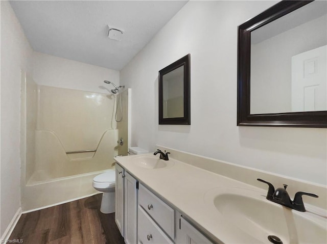 bathroom featuring double vanity, wood finished floors, toilet, and a sink