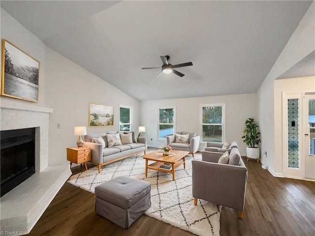 living area featuring a brick fireplace, a ceiling fan, lofted ceiling, and wood finished floors