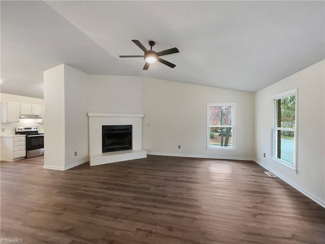 unfurnished living room with baseboards, dark wood finished floors, a fireplace, ceiling fan, and vaulted ceiling