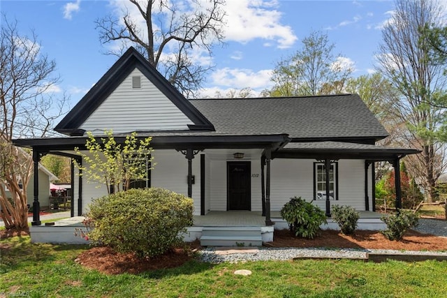 view of front of house featuring covered porch, a shingled roof, and a front yard