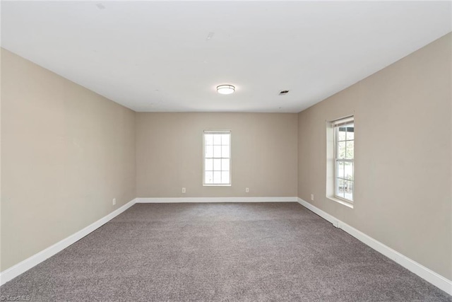 empty room with dark colored carpet and baseboards