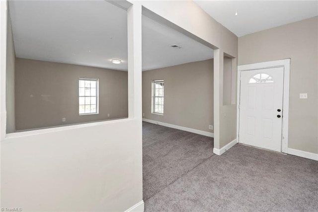 carpeted entryway with baseboards and plenty of natural light