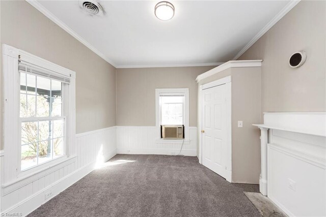 carpeted empty room with cooling unit, a wainscoted wall, ornamental molding, and visible vents