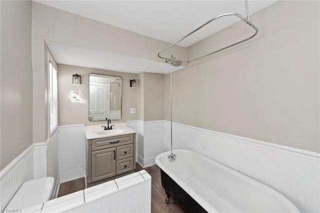 bathroom featuring a wainscoted wall, wood finished floors, toilet, and vanity